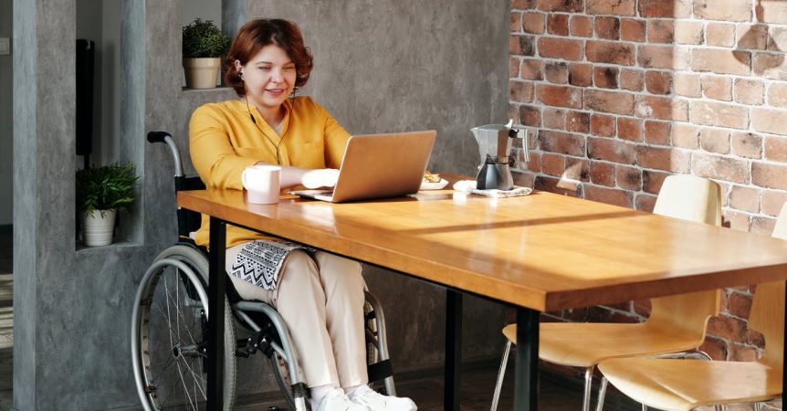 woman sitting on wheelchair while using laptop